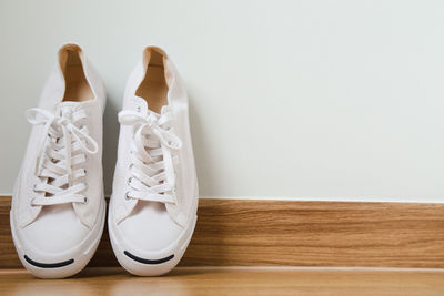 Close-up of canvas shoes on hardwood floor against white wall