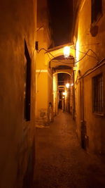 Empty alley amidst illuminated buildings at night