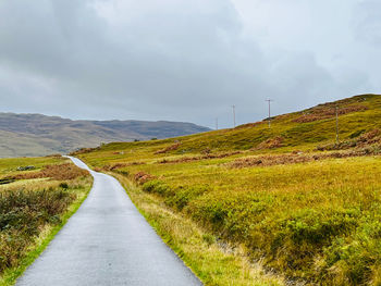 Road amidst field against sky