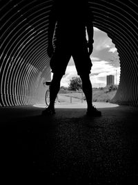 Low section of silhouette man standing on bridge