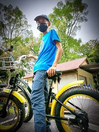 Man standing by bicycle against trees