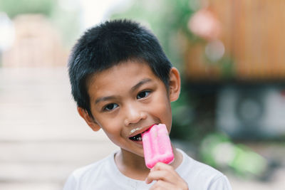 Boy looking away while eating popsicle