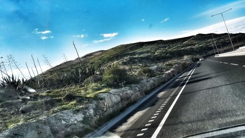 Road by mountain against sky