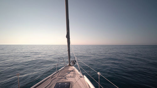 Sailboat sailing on sea against clear sky during sunset
