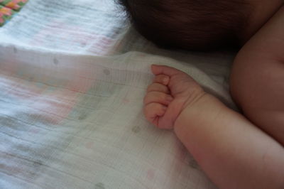 Close-up of baby hand on bed