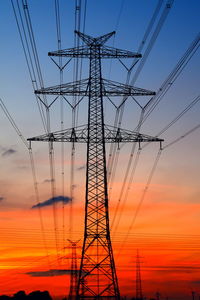 Low angle view of electricity pylon against sky during sunset