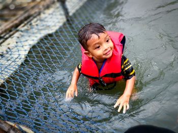 Boy wearing life jacket in pond