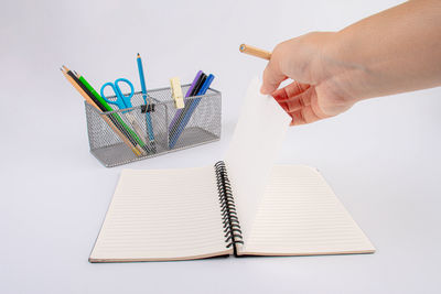 Cropped hand writing in book on table