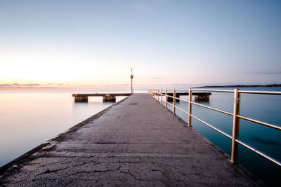 Pier over sea against sky during sunset