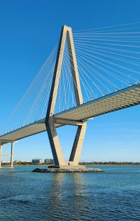 Low angle view of bridge over river against clear blue sky