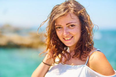 Portrait of smiling young woman against sea