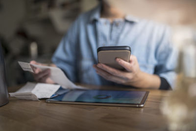 Woman organizing household budget with digital tablet and smartphone