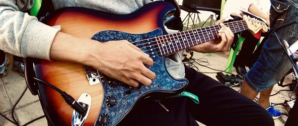 Midsection of man playing guitar