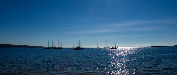 Sailboats in sea against blue sky