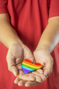 Midsection of man holding heart shape rainbow flag