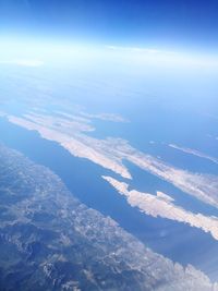 Aerial view of sea and landscape against blue sky