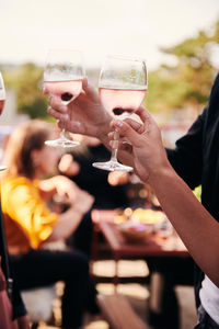 Cropped hands of friends holding wineglasses during social gathering on terrace