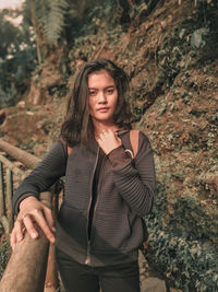 Portrait of young woman standing by railing