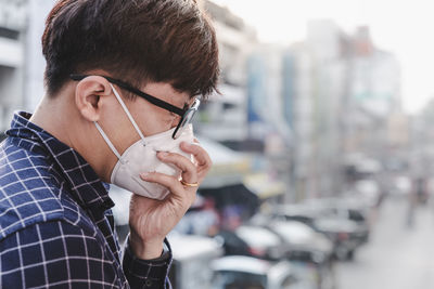 Side view of man wearing mask sneezing outdoors