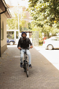 Side view of man riding bicycle on street in city