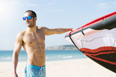 Full length of shirtless man standing at beach against sky