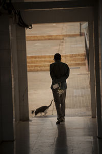 Rear view of man with dog walking on floor