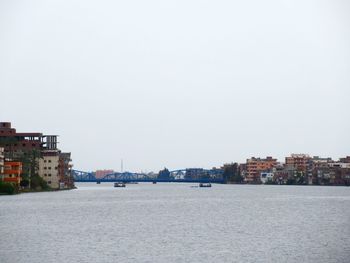 Buildings by sea against clear sky