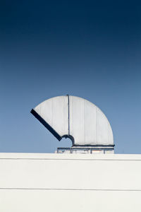 Low angle view of telephone pole against clear blue sky