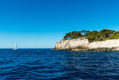 Sailboat sailing in sea against clear blue sky