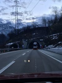 Cars on road against cloudy sky