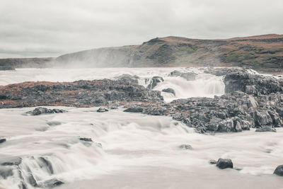 Scenic view of waterfall against sky