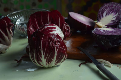Red radicchio, knife, cut red cabbage, red onion, on bamboo cutting board on light green surface