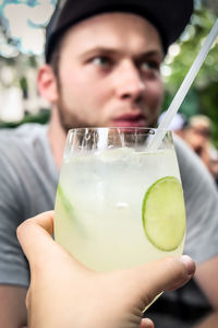 Cropped hand of woman holding drink by man at restaurant