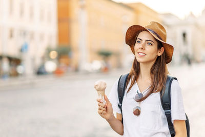 Young woman wearing hat standing in city