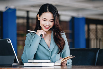 Young woman using mobile phone while sitting on table