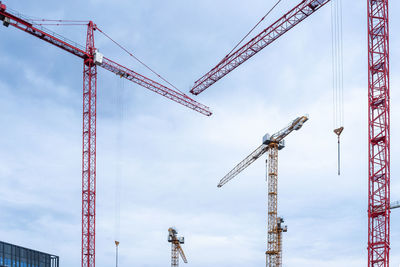 Low angle view of cranes against sky