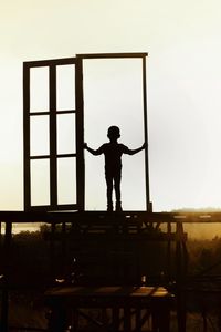 Silhouette boy standing against clear sky