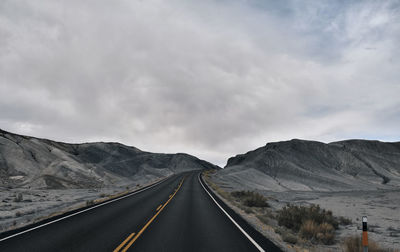 Road leading towards mountains against sky