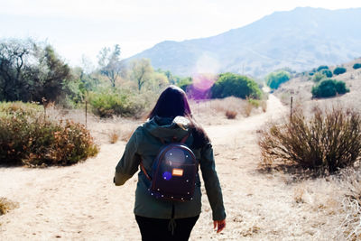 Rear view of woman standing on desert against mountain