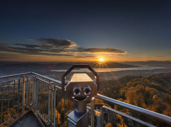 Close-up of coin-operated binoculars against sky during sunset