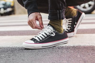 Low section of man tying shoelace on road