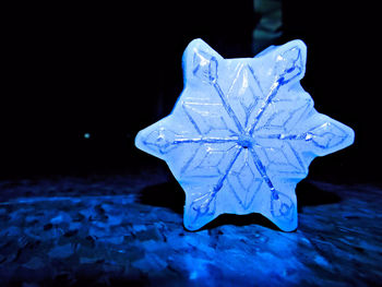 Close-up of snowflakes on leaf against black background