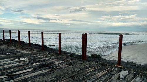 Wooden posts on beach against sky