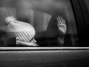 Woman seen through wet glass window