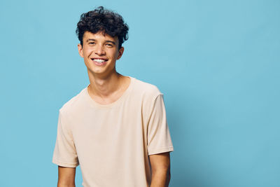 Portrait of young man standing against blue background