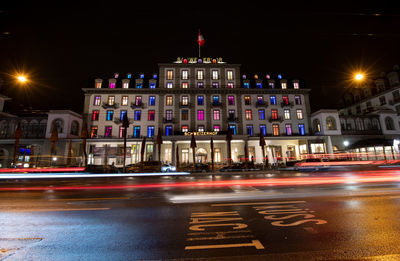 Light trails on city street by buildings at night