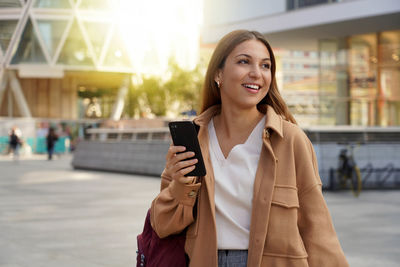 Smiling woman using mobile phone on street