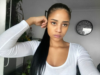 Portrait of a young woman against wall at home