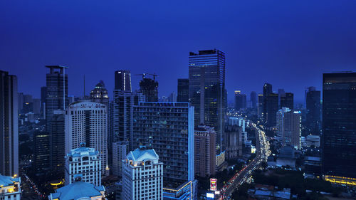 Illuminated buildings in city against blue sky at dusk