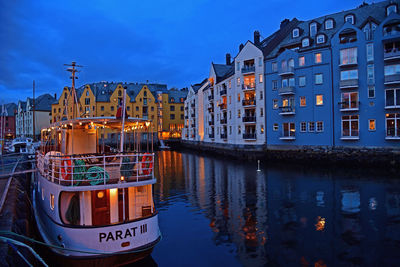 Boats moored in canal by buildings against sky in city